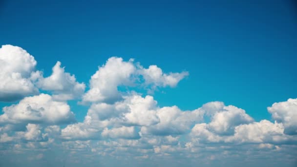 Weiße, flauschige Wolken schweben langsam durch den blauen Tageshimmel — Stockvideo