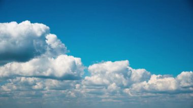 White fluffy clouds slowly float through the blue daytime sky timelapse. Beautiful skies are moving. Airy snow-white clouds move to the side.