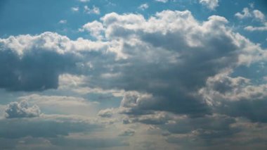 Beyaz kabarık bulutlar mavi gündüz vakti gökyüzünde yavaşça süzülür. Güzel gökyüzü hareket ediyor. Kar beyazı bulutlar yana doğru hareket ediyor..
