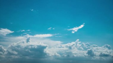 White fluffy clouds slowly float through the blue daytime sky timelapse. Beautiful skies are moving. Airy snow-white clouds move to the side.