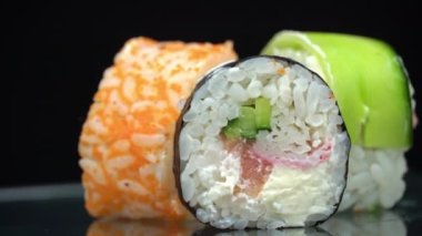 Taze suşi rulosu maki dönüşümlü yakın çekim. Balıktan suşi, somon, pirinç, salatalık. Suşi restoranı, suşi teslimatı. Lezzetli Japon yemekleri. Dilimlenmiş rulo.
