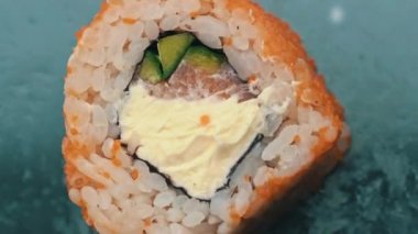Susam tohumlu taze suşi rulosu yakın çekim dönüşümlü. Balıktan suşi, somon, pirinç, salatalık. Suşi restoranı, suşi teslimatı. Lezzetli Japon yemekleri. Dilimlenmiş rulo.