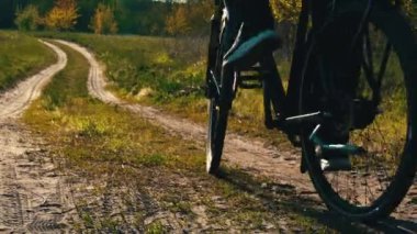 Genç adam gün batımında ormanda tozlu bir patika boyunca bisiklet sürüyor. Ormanda bisiklete binen bir adam sağlıklı bir hayat sürüyor. Spor, eğlence ve hobi, sağlık sigortası, fitness. Seyahat.