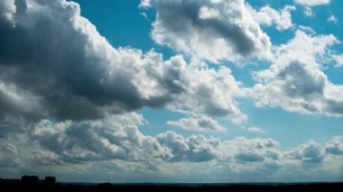 Beyaz kabarık bulutlar mavi gündüz vakti gökyüzünde yavaşça süzülür. Güzel gökyüzü hareket ediyor. Kar beyazı bulutlar yana doğru hareket ediyor..