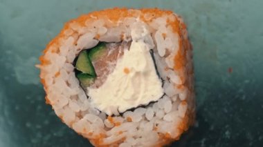 Susam tohumlu taze suşi rulosu yakın çekim dönüşümlü. Balıktan suşi, somon, pirinç, salatalık. Suşi restoranı, suşi teslimatı. Lezzetli Japon yemekleri. Dilimlenmiş rulo.