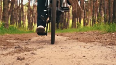 Genç adam gün batımında ormanda tozlu bir patika boyunca bisiklet sürüyor. Ormanda bisiklete binen bir adam sağlıklı bir hayat sürüyor. Spor, eğlence ve hobi, sağlık sigortası, fitness. Seyahat.