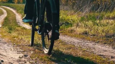 Genç adam gün batımında ormanda tozlu bir patika boyunca bisiklet sürüyor. Ormanda bisiklete binen bir adam sağlıklı bir hayat sürüyor. Spor, eğlence ve hobi, sağlık sigortası, fitness. Seyahat.