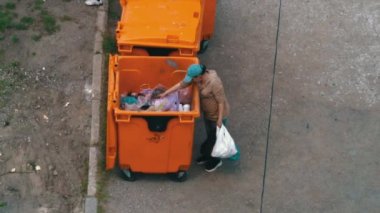 Evsiz adam çöp tenekesini karıştırıp yiyecek falan arıyor. Zavallı adam bir şey bulmak için çöplüğü kazıyor. Belirli bir ikamet yeri olmayan birinin yoksul varlığı.