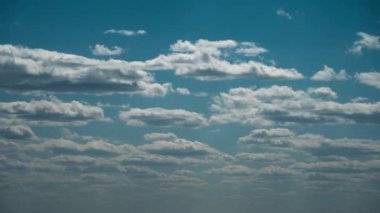 Beyaz kabarık bulutlar mavi gündüz vakti gökyüzünde yavaşça süzülür. Güzel gökyüzü hareket ediyor. Kar beyazı bulutlar yana doğru hareket ediyor..