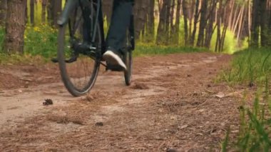 Genç adam gün batımında ormanda tozlu bir patika boyunca bisiklet sürüyor. Ormanda bisiklete binen bir adam sağlıklı bir hayat sürüyor. Spor, eğlence ve hobi, sağlık sigortası, fitness. Seyahat.