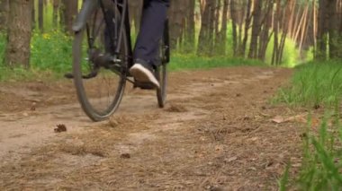 Genç adam gün batımında ormanda tozlu bir patika boyunca bisiklet sürüyor. Ormanda bisiklete binen bir adam sağlıklı bir hayat sürüyor. Spor, eğlence ve hobi, sağlık sigortası, fitness. Seyahat.