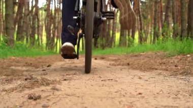 Genç adam gün batımında ormanda tozlu bir patika boyunca bisiklet sürüyor. Ormanda bisiklete binen bir adam sağlıklı bir hayat sürüyor. Spor, eğlence ve hobi, sağlık sigortası, fitness. Seyahat.