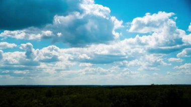 Beyaz kabarık bulutlar mavi gündüz vakti gökyüzünde yavaşça süzülür. Güzel gökyüzü hareket ediyor. Kar beyazı bulutlar yana doğru hareket ediyor..