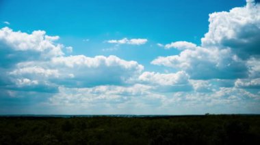 Beyaz kabarık bulutlar mavi gündüz vakti gökyüzünde yavaşça süzülür. Güzel gökyüzü hareket ediyor. Kar beyazı bulutlar yana doğru hareket ediyor..