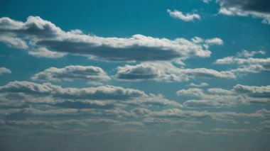 Beyaz kabarık bulutlar mavi gündüz vakti gökyüzünde yavaşça süzülür. Güzel gökyüzü hareket ediyor. Kar beyazı bulutlar yana doğru hareket ediyor..