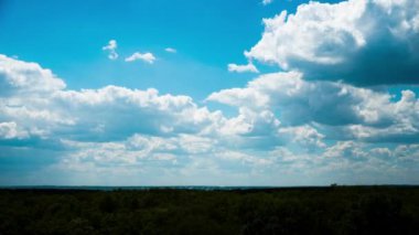 Beyaz kabarık bulutlar mavi gündüz vakti gökyüzünde yavaşça süzülür. Güzel gökyüzü hareket ediyor. Kar beyazı bulutlar yana doğru hareket ediyor..