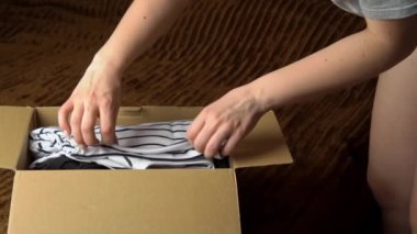 Genç bir kız içinde bir şeyler olan bir paketi parçalara ayırıyor ve elbiseleri inceliyor. Güzel elbiseli kahverengi bir kutu bir kadını muayene eder ve dener. Nesnelerin internet ve posta yoluyla teslimatı.