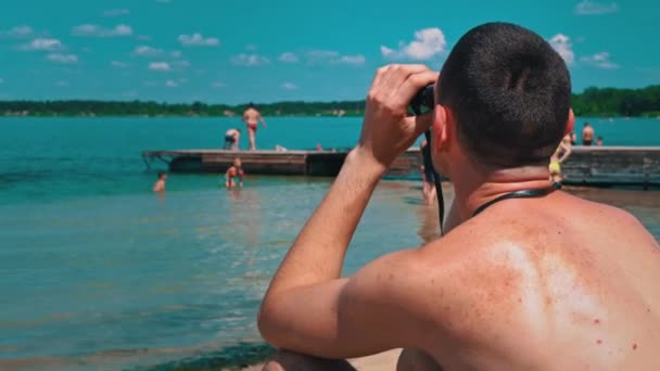 Hombre Playa Traje Baño Está Vigilando Alguien Través Prismáticos Salvavidas — Vídeo de stock