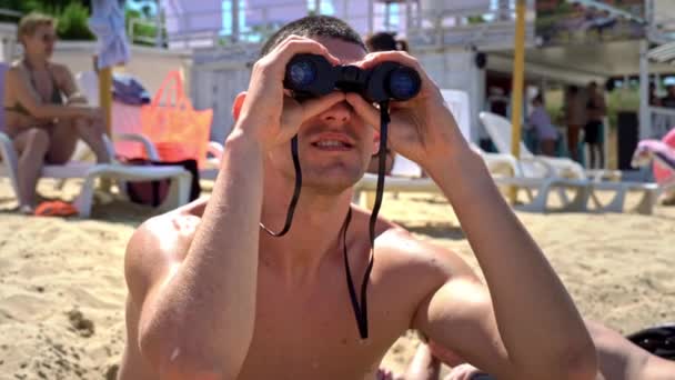 Facet Plaży Kąpielówkach Obserwuje Kogoś Przez Lornetkę Ratownik Plaży Utrzymuje — Wideo stockowe