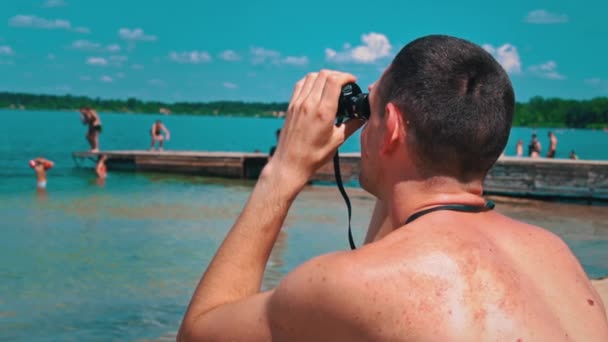 팬츠를 해변에 남자가 쌍안경으로 누군가를보고 있습니다 구조대 질서를 유지하고 호기심많은 — 비디오