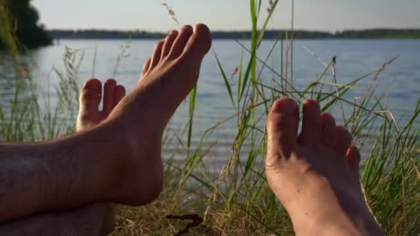 川の近くに自然の中で愛の男と女の裸の足 自然との愛のカップルのリラクゼーション 静けさと孤独 ビーチ 日焼け — ストック動画