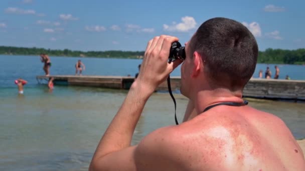 Hombre Playa Traje Baño Está Vigilando Alguien Través Prismáticos Salvavidas — Vídeos de Stock