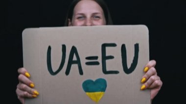 Kızın elinde Ukrayna 'nın Avrupa Birliği' ne aday olduğu için sevinen bir poster var. Ukraynalılar artık Avrupa 'nın koruması altındalar. Savaş yok, insanlar şiddet uyguluyor. Bir kadının neşesi.