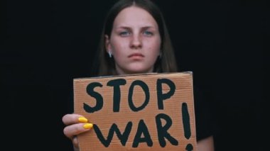 Ukraynalı zavallı kız askeri çatışmayı protesto ediyor. Genç bir kadın, siyah bir arkaplanda savaşı durdurmak için yazıyla sancak kaldırıyor. Kriz dünyası.