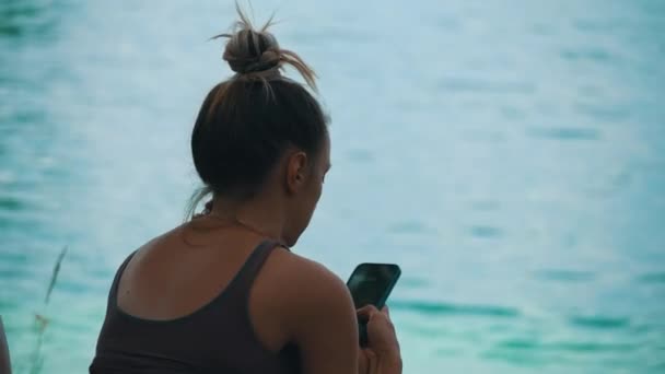 Young Woman Cap Sits River Smartphone Nature Calmness Relaxation Solitude — Vídeo de Stock
