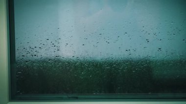 Pencere pervazına ve pencere pervazına yağmur damlaları düşer. Şehir manzarasında yağmurlu bir hava var. Bardaktan boşanırcasına yağmur yağıyor..