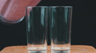 Meyveli milkshake bardaklara dökülür. İki bardak taze milkshake. Meyve ve meyveli yaz içeceği..