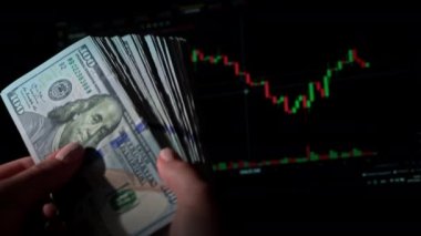 Borsa grafiğinin arka planında bir el dolusu dolar var. İnsanlar elden ele büyük miktarda para geçiriyorlar. Kripto para birimleri. Şifreli para biriminin değeri dijital para yükseliyor.