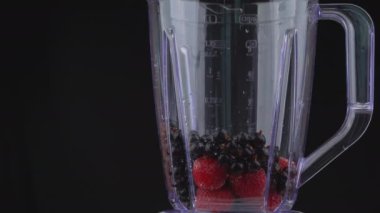 Süt blender kasesine böğürtlenlerle doldurulur. Büyük bir blender kasesinde çilek, frenk üzümü ve süt. Taze meyveler milkshake 'e dönüşmeye hazır..