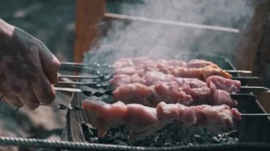 Meat barbecue is fried on skewers and in the grill in nature. Cooking delicious barbecue in nature. Delicious food on a metal skewer in a barbecue. Picnic time. Street eatery. Food Festival. Pork on