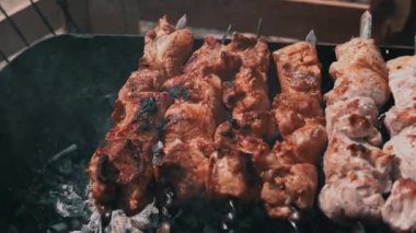 Meat barbecue is fried on skewers and in the grill in nature. Cooking delicious barbecue in nature. Delicious food on a metal skewer in a barbecue. Picnic time. Street eatery. Food Festival. Pork on