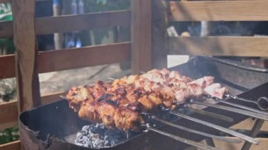 Meat barbecue is fried on skewers and in the grill in nature. Cooking delicious barbecue in nature. Delicious food on a metal skewer in a barbecue. Picnic time. Street eatery. Food Festival. Pork on