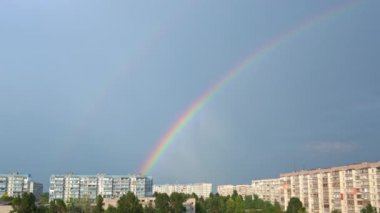 Gökkuşağı mavi gökyüzünde, şehir manzaralı. Gökteki yağmurdan sonra gökkuşağının yedi rengi. Bulutsuz gökkuşağı.