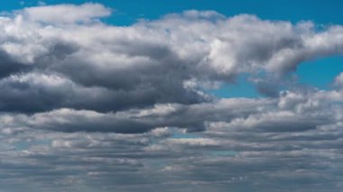 Beyaz kabarık bulutlar mavi gündüz vakti gökyüzünde yavaşça süzülür. Güzel gökyüzü hareket ediyor. Kar beyazı bulutlar yana doğru hareket ediyor..