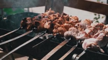 Meat barbecue is fried on skewers and in the grill in nature. Cooking delicious barbecue in nature. Delicious food on a metal skewer in a barbecue. Picnic time. Street eatery. Food Festival. Pork on