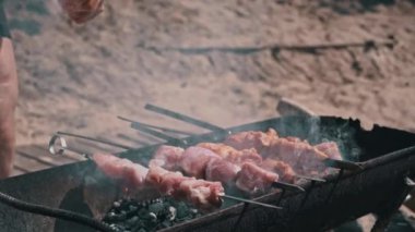 Meat barbecue is fried on skewers and in the grill in nature. Cooking delicious barbecue in nature. Delicious food on a metal skewer in a barbecue. Picnic time. Street eatery. Food Festival. Pork on