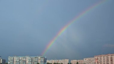 Gökkuşağı mavi gökyüzünde, şehir manzaralı. Gökteki yağmurdan sonra gökkuşağının yedi rengi. Bulutsuz gökkuşağı.