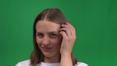Güzel bir kız yeşil arka planda gülümser ve sevinir. Yeşil ekranda izole edilmiş mutlu, genç bir kadın, krom cay.