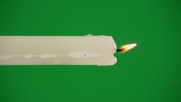 黄色の色合いの白いパラフィンキャンドルは緑の背景に燃えます 一本の蝋ろうそくが動かずに燃え 火を放つ — ストック動画