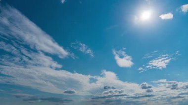 White fluffy clouds slowly float through the blue daytime sky timelapse. Beautiful skies are moving. Airy snow-white clouds move to the side.