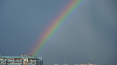 Gökkuşağı mavi gökyüzünde, şehir manzaralı. Gökteki yağmurdan sonra gökkuşağının yedi rengi. Bulutsuz gökkuşağı.