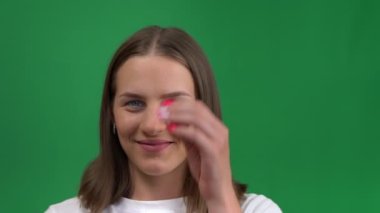 Güzel bir kız yeşil arka planda gülümser ve sevinir. Yeşil ekranda izole edilmiş mutlu, genç bir kadın, krom cay.