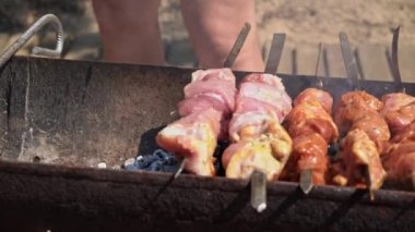 Meat barbecue is fried on skewers and in the grill in nature. Cooking delicious barbecue in nature. Delicious food on a metal skewer in a barbecue. Picnic time. Street eatery. Food Festival. Pork on