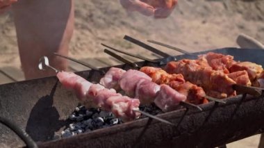Meat barbecue is fried on skewers and in the grill in nature. Cooking delicious barbecue in nature. Delicious food on a metal skewer in a barbecue. Picnic time. Street eatery. Food Festival. Pork on