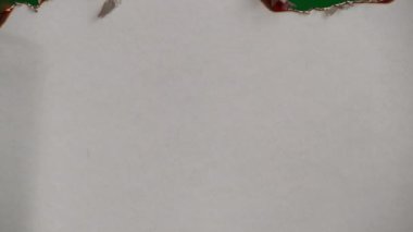 White paper burns from above on a green background copy space. The sheet of paper burns and reveals a green background for pasting.