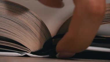 Beyaz kitaptaki sayfaları yavaş çekimde kapatıyoruz. Kitap okumak, istihbarat. Sayfalar peş peşe akıyor. Kadınların elleri kitap sayfalarını karıştırır..